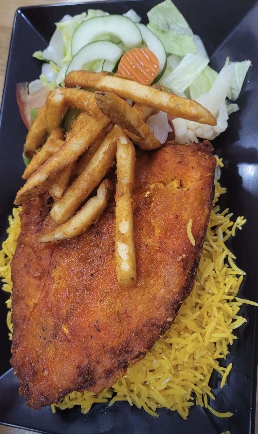 Fried tilapia fish over rice with fries and salad